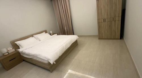 Schlafzimmer mit einem weißen Bett und einem Holzschrank in der Unterkunft Hotel Apartment - 12 - LAvner Al Moteab in Riad