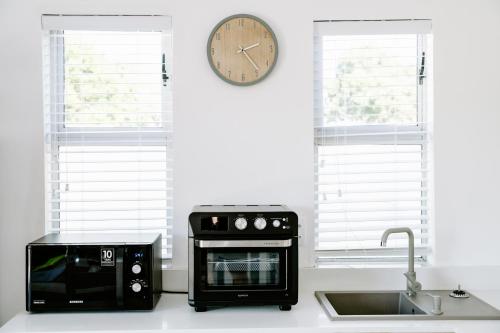 a kitchen with a microwave and a clock on the wall at Huis Marais in Herolds Bay