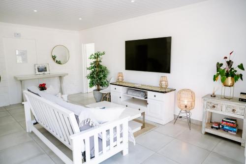 a white living room with a tv and a tub at Huis Marais in Herolds Bay