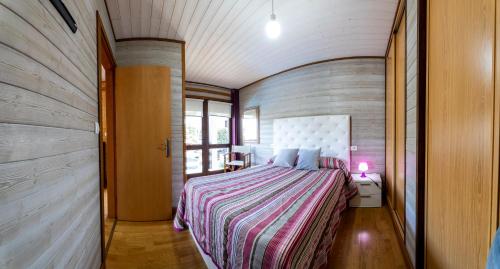 a bedroom with a bed with a striped bedspread at CABAÑA VILA DO MAR in Baiona