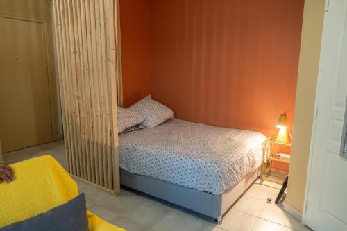 a small bedroom with a bed and an orange wall at Studio Aline in Saint-Denis
