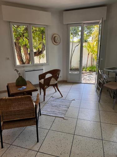 een woonkamer met stoelen en een tafel en ramen bij Villa Butterfly - Jardin - Plage 400m in Juan-les-Pins