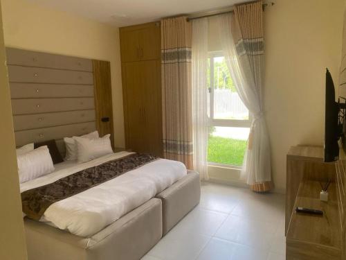 a bedroom with a large bed and a window at Golf Mews Inspired Living in Benin City