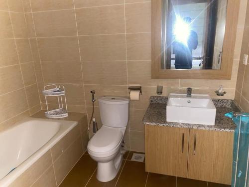 a person taking a picture of a bathroom with a toilet and sink at Golf Mews Inspired Living in Benin City
