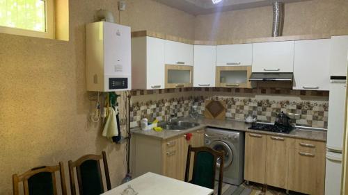 eine Küche mit weißen Schränken, einer Spüle und einem Geschirrspüler in der Unterkunft Sheki Guest House in Şəki