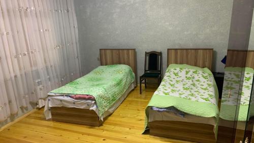シェキにあるSheki Guest Houseのベッド2台と鏡が備わる客室です。