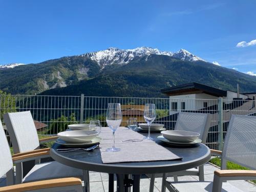 a table with wine glasses on a balcony with a mountain at Apart Mark, Stanz bei Landeck - Moderne Wohnung in sonniger Lage in Stanz bei Landeck