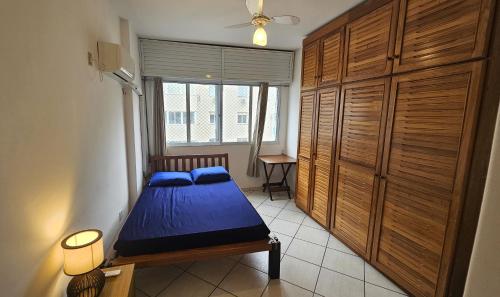 Un dormitorio con una cama azul y una ventana en Pé na areia - Praia Pitangueiras - Beach Host, en Guarujá
