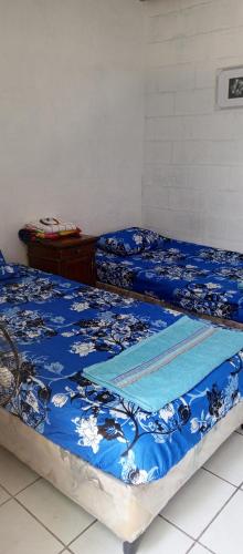 two beds in a room with blue comforter at Mini casa a dos cuadras de la playa, en medio del comercio local in La Libertad