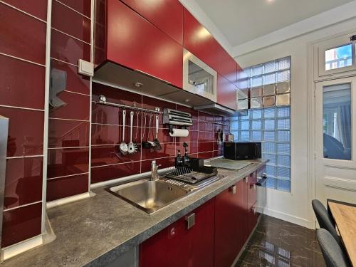 uma cozinha com paredes vermelhas e um lavatório de aço inoxidável em DEAUVILLE Maison plein centre, ideale famille ! em Deauville