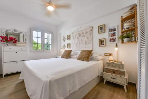a white bedroom with a large bed and a dresser at Moraira Apartamiento Ocarrol Rent in Teulada