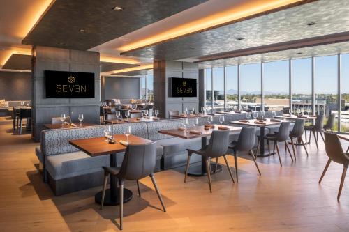 a restaurant with tables and chairs and windows at Caesars Republic Scottsdale, a Hilton Hotel in Scottsdale