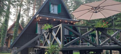 ein kleines Haus mit einem Sonnenschirm auf einer Terrasse in der Unterkunft Domek letniskowy nad jeziorem, Mazury in Teerau