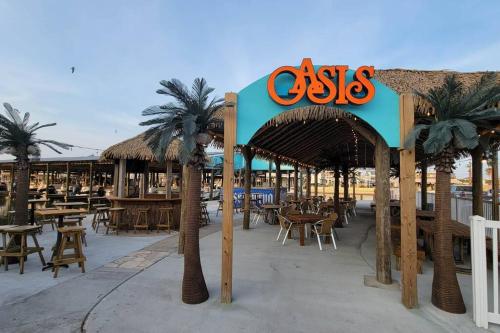 a restaurant with palm trees and tables and a sign at 6 BR Beach view -Sleeps 14 -Rolling with the flow in Galveston