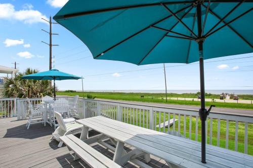 a wooden deck with a bench and an umbrella at 6 BR Beach view -Sleeps 14 -Rolling with the flow in Galveston