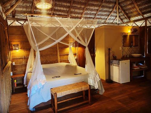 1 dormitorio con cama con dosel en una habitación en Caju Bangalôs, en Ponta do Anel