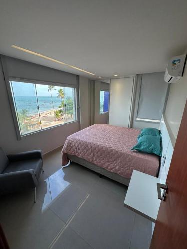 a bedroom with a bed and a view of the beach at Apartamento Beira Mar em Maceió in Maceió