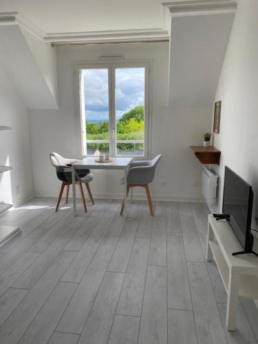 - un salon blanc avec une table et une télévision dans l'établissement Studio entièrement refait à neuf, à Bagnoles-de-l'Orne