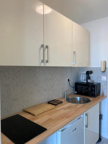 un comptoir de cuisine avec un évier et un micro-ondes dans l'établissement Studio entièrement refait à neuf, à Bagnoles-de-l'Orne