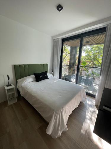 a bedroom with a white bed and a large window at Departamento Nuevo en Palermo Soho in Buenos Aires