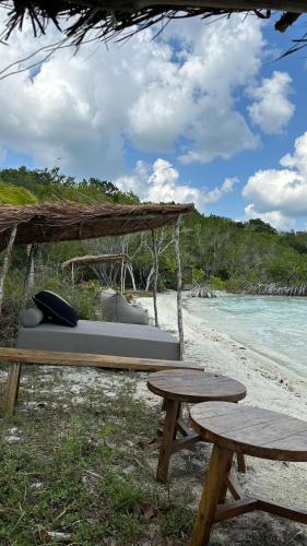 a picnic table and two benches on a beach at Casa Vive Bacalar in Bacalar