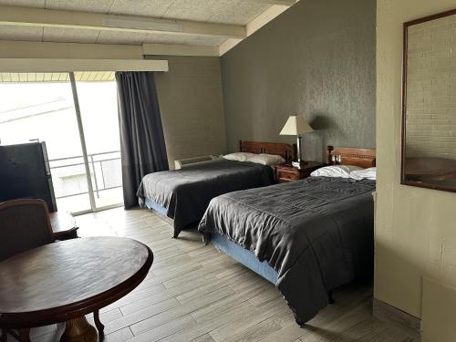 um quarto de hotel com duas camas e uma mesa em Bravo Inn Greensboro em Greensboro