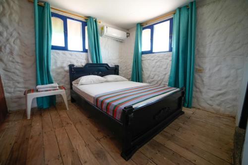 a bedroom with a bed with green curtains and a table at El Remanso del Santuario in Camarones