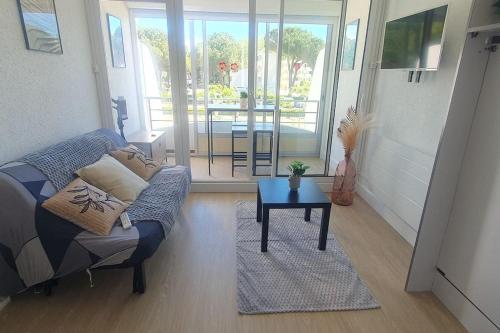 un salon avec un canapé et une table dans l'établissement Studio rêve de mer 25 m2, centre ville, parking, cosy neuf, à La Grande Motte