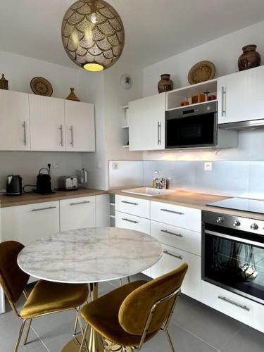 - une cuisine blanche avec une table, des chaises et un four micro-ondes dans l'établissement Appart La Mantilla, wifi, clim, parking, Netflix, à Montpellier