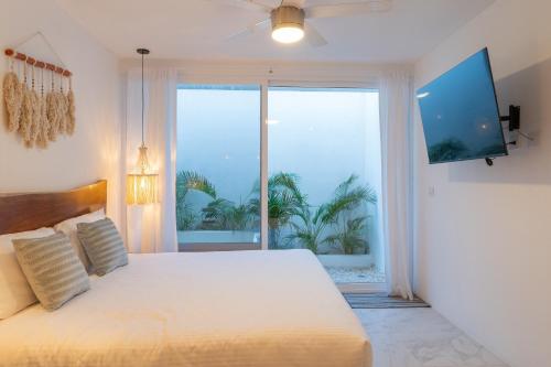 une chambre avec un grand lit et une grande fenêtre dans l'établissement Studios in Tulum by Casago, à Tulum