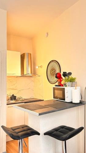 une cuisine avec un comptoir et deux tabourets dans l'établissement L'abri douillet, à Montauban