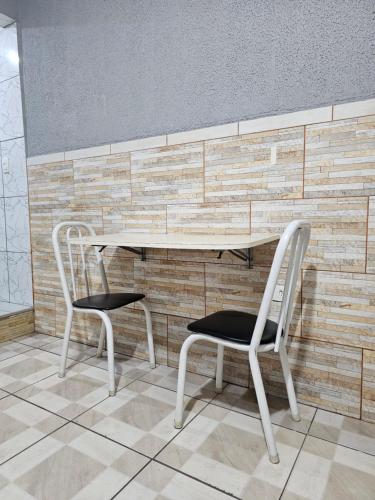 een tafel en twee stoelen voor een bakstenen muur bij QUARTO ACONCHEGANTE in Guarulhos