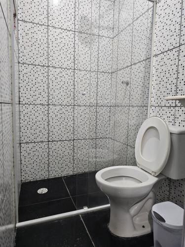 a bathroom with a toilet and a tiled wall at QUARTO ACONCHEGANTE in Guarulhos