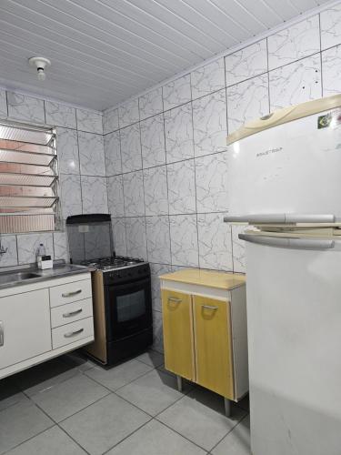 een keuken met een fornuis en een koelkast bij QUARTO ACONCHEGANTE in Guarulhos