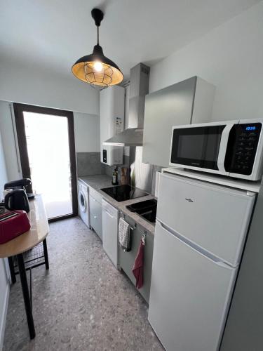 La cuisine est équipée d'un réfrigérateur blanc et d'un four micro-ondes. dans l'établissement Le Cosy Rionde : Apt 6 Prs, 2 ch, parking, clim, à Antibes