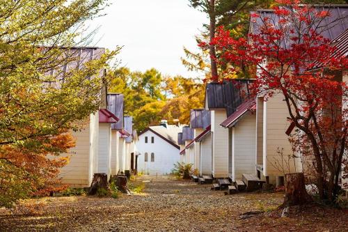 a row of white buildings with trees in the background at Shinei Kiyosato Campsite - Vacation STAY 15467v in Hokuto