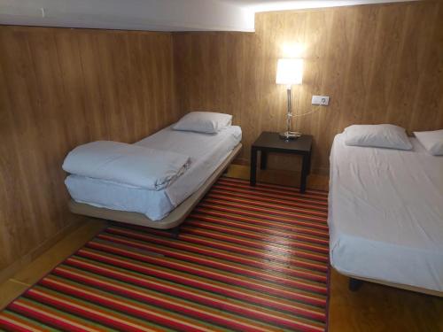 a hotel room with two beds and a table with a lamp at Estudios sol in Madrid