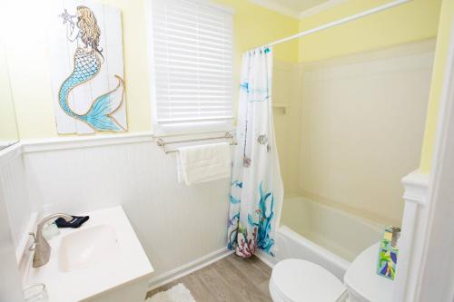 Lorraine's Beach Cottage في كيور بيتش: حمام مزود بستارة دش عليها رسمة حصان البحر وحوض غسيل