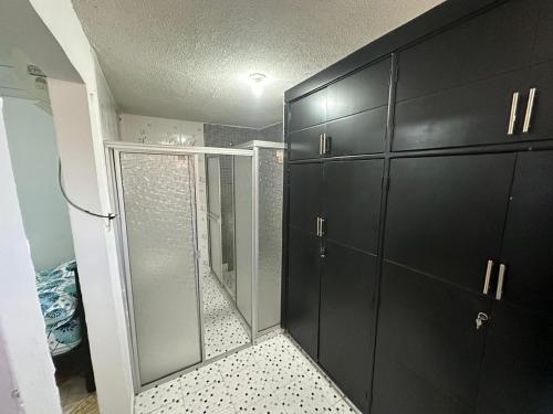 baño con armarios negros y ducha acristalada en Hospedaje central, Mary Sicarare en Valledupar