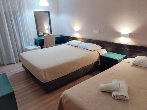 a hotel room with two beds and a mirror at Plaza Hotel in Alexandroupoli