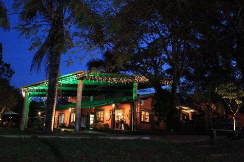 a house with a green roof and palm trees at night at Hotel Fazenda Santa Monica in Louveira