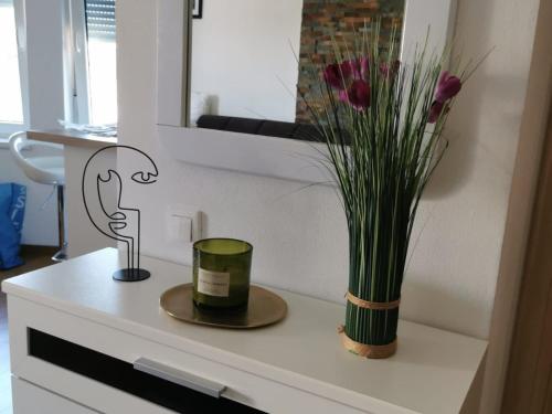 a vase of flowers and a candle on a table at New modern apartment in Selce
