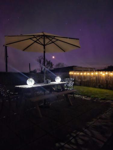 a picnic table with an umbrella and lights at night at Farnaught Farmhouse Apartment, Lough Rynn, Mohill in Farnaght
