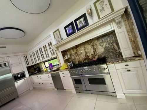 a kitchen with white cabinets and a stove top oven at Vila Manor in Midrakh ‘Oz