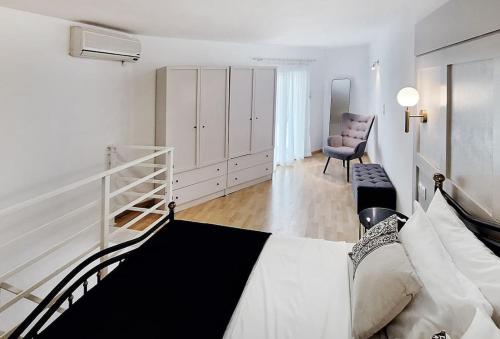 a white bedroom with a bed and a chair at Achlia Sea Side Retreat 3 in Achlia