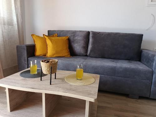 a blue couch with two glasses of orange juice on a coffee table at VICTORY SUITES in Samothráki