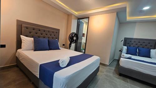 a bedroom with two beds with blue and white pillows at Andaliving Campo Valdés in Medellín