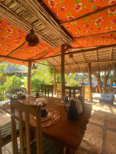 a wooden table with chairs and an umbrella at Caju Bangalôs in Ponta do Anel