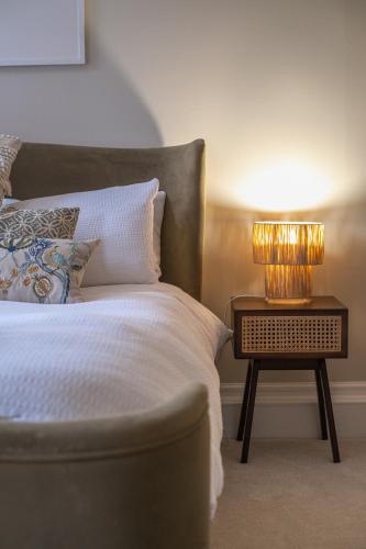 a bed with a side table with a lamp on it at The Ballroom - Huge 2 Bed, Lichfield City Centre in Lichfield