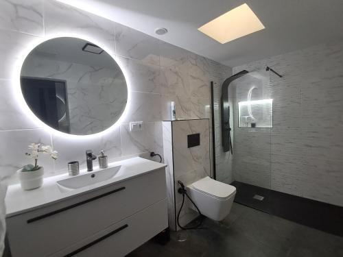 a bathroom with a sink and a toilet and a mirror at Casa Reina Tauro with private pool in La Playa de Tauro